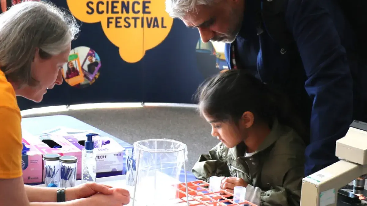 Little girl and her dad engage with researcher at an exhibition table for Edinburgh Science Festival 