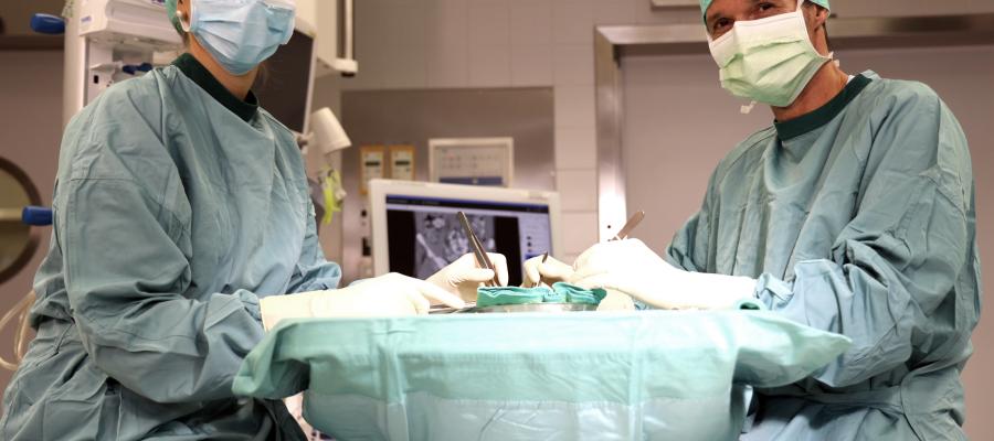 Two surgeons working on an operating table, looking at the camera.