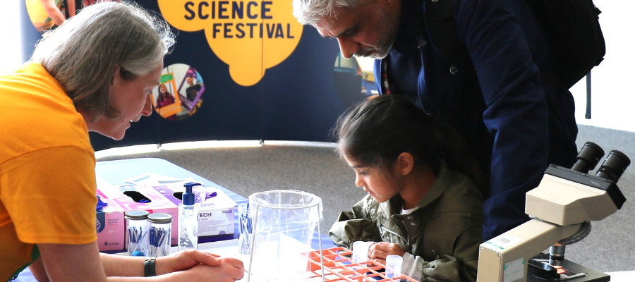Little girl and her dad engage with researcher at an exhibition table for Edinburgh Science Festival 