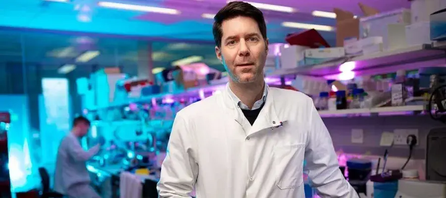 Steve Pollard stands in a white coat in a lab