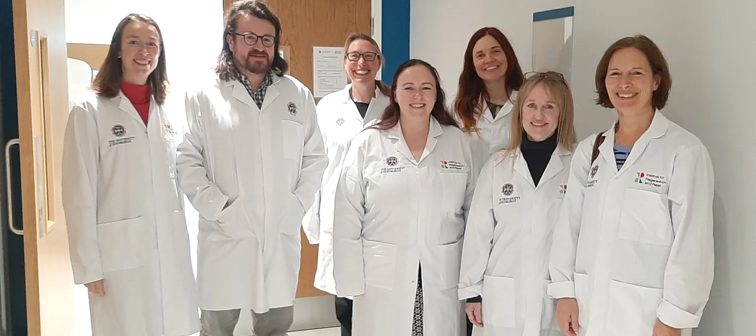 Joy and seven members of SPICe standing in lab coats within IRR