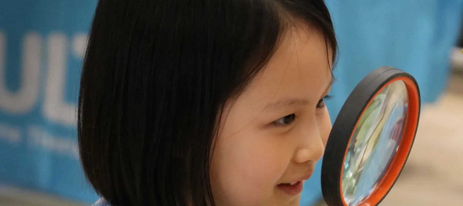Child looking through a magnifying glass closeup