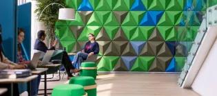 co-working space with some people working on laptops and a senior PI in conversation with a student