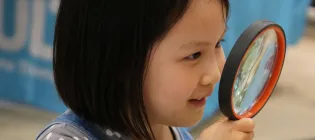 Girl holding up a magnifying glass