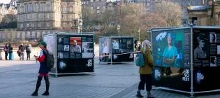 Tourists observe the outdoor photo exhibition on The Mound, Edinburgh