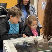 Two children and their mother looking down at a table laser game