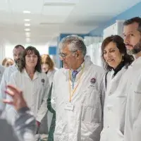 A dozen adults wearing lab coats on a facility tour