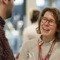Woman smiling in conversation with busy room behind her
