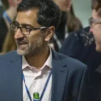 Man smiling in conversation holding beer bottle