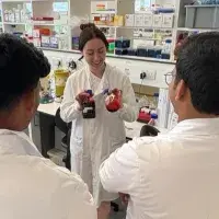 OSCAR Young Leaders in lab coats watching a demonstration in the lab
