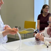 A girl holding a tube with small silver and red beads inside 