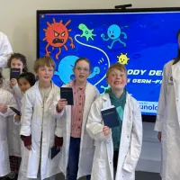 A group photo of 4 workshop deliverers and 6 children smiling and some holding their passports up