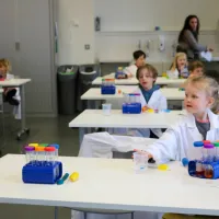 Tables with children sat at, listening to instructions