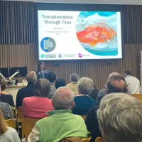 Tilly Mason at the front of the room presenting with the photo being taken at the back of the room, with backs of heads in shot