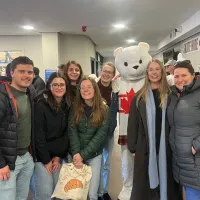 a group of people standing with a polar bear mascot in a Canada jersey