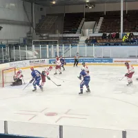 an ice hockey game in action with players in blue, and red and white