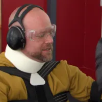 Someone wearaing neckbrace, headphones and a low-mobility suit