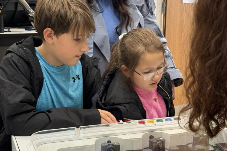 Two children and their mother looking down at a table laser game