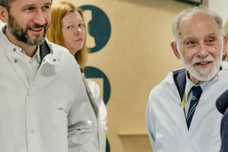 Three adults wearing lab coats on a facility tour