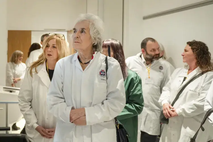A dozen adults wearing lab coats on a facility tour
