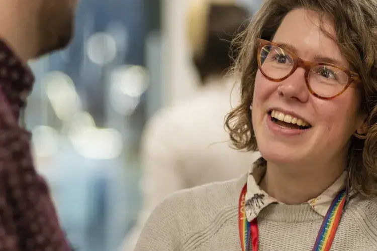 Woman smiling in conversation with busy room behind her