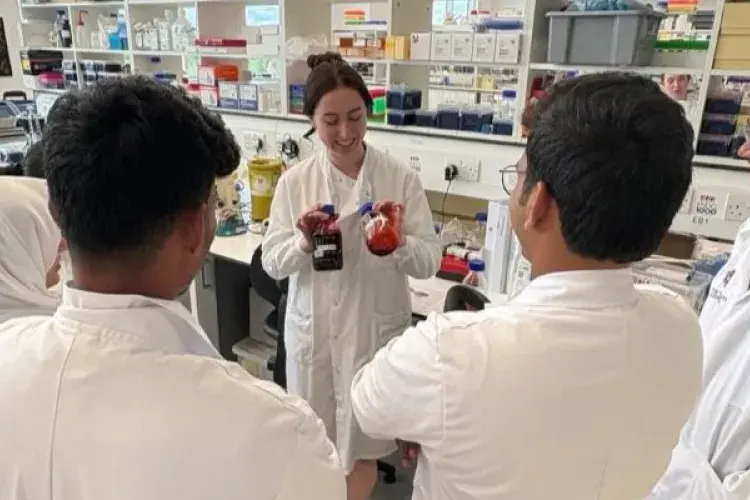 OSCAR Young Leaders in lab coats watching a demonstration in the lab