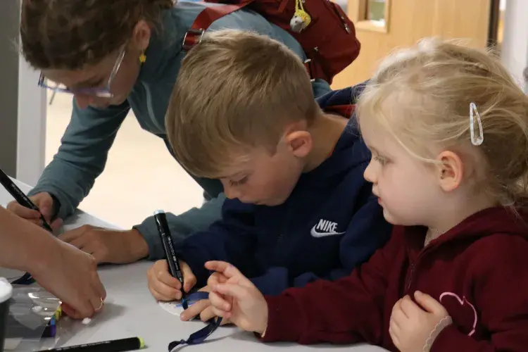 Three children drawing with pens