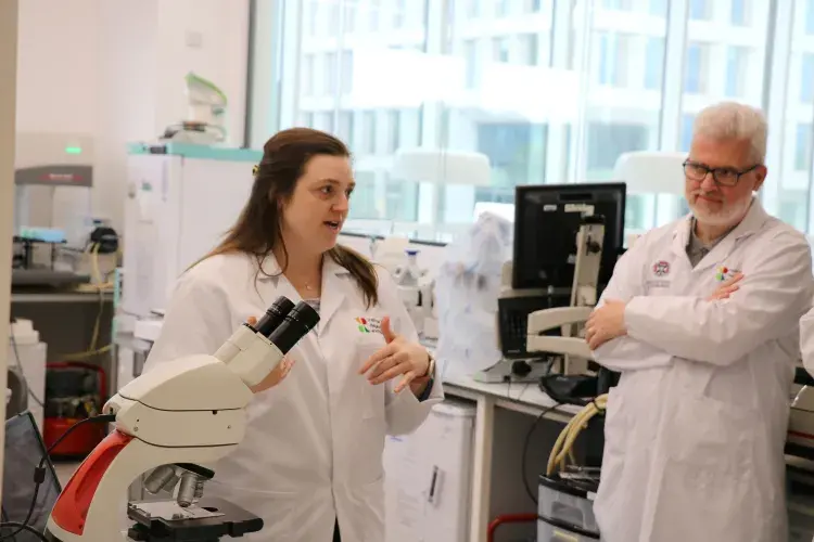 Researcher in lab coat mid-sentence in the lab