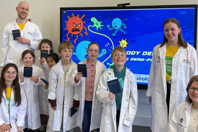 A group photo of 4 workshop deliverers and 6 children smiling and some holding their passports up