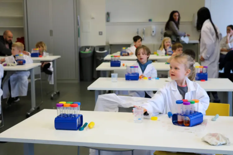 Tables with children sat at, listening to instructions