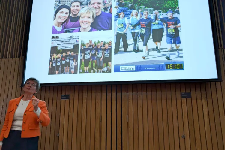 Lorna Marson presenting in front of a screen of fundraising photos