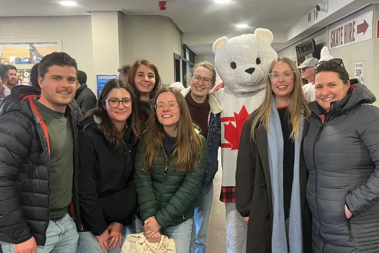 a group of people standing with a polar bear mascot in a Canada jersey