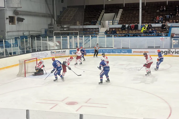 an ice hockey game in action with players in blue, and red and white