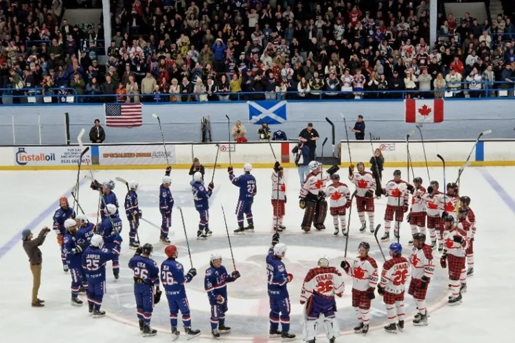 two ice hockey teams standing on the ice in a large circle with their sticks raised in the air.