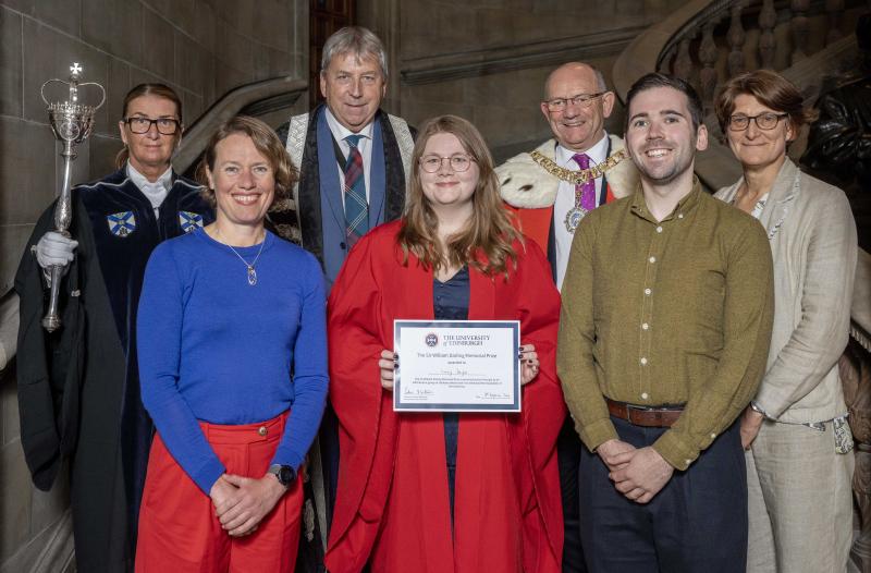 Front row (left to right): Cathy Southworth, Lucy Doyle (in red academic robes holding a certificate), Dom Cairn-Gibson. Back row: Woman in academic robes holding a sceptre, Peter Mathieson (in Principal academic robes), man (in fur lined red robe and chain),  Marieke Hoeve.