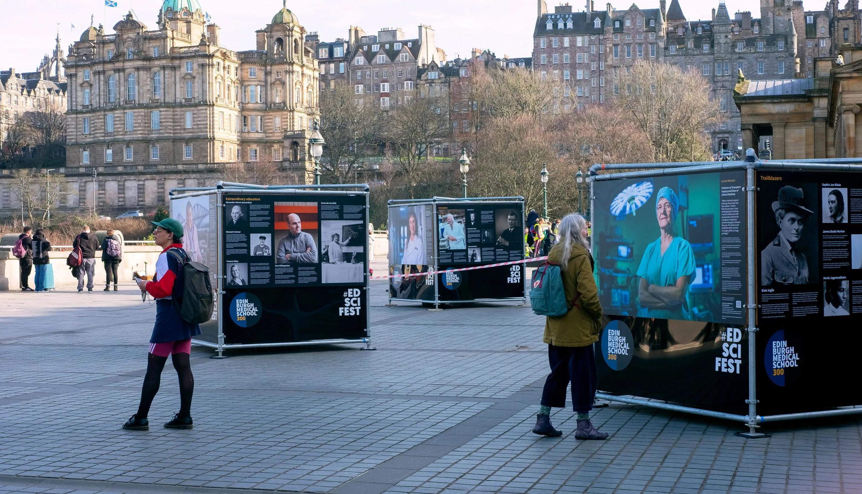 Tourists observe the outdoor photo exhibition on The Mound, Edinburgh