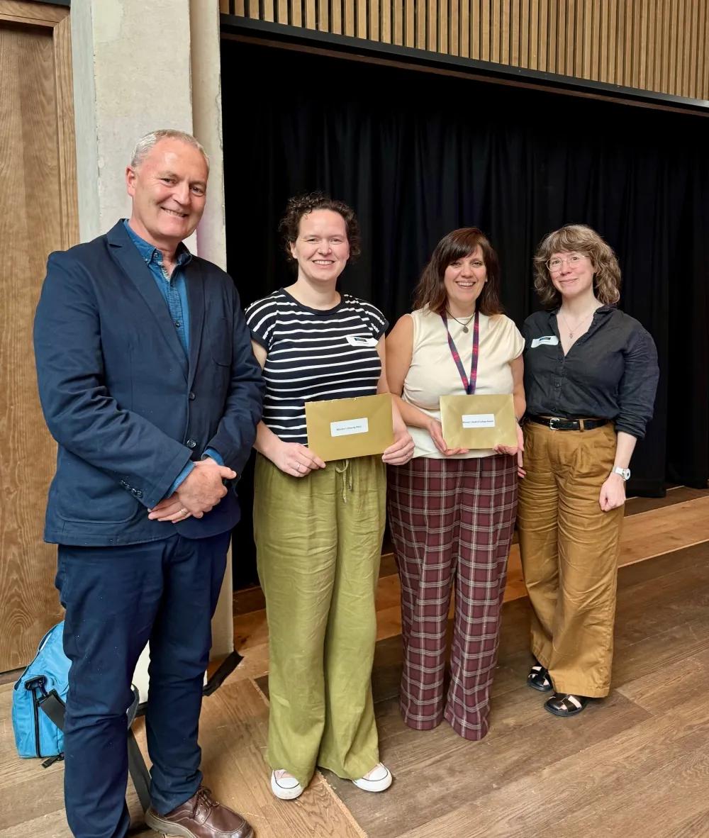 Stuart Forbes, Lauren Melrose, Shonna Johnston, and Florence Gohard standing in a line in front of a black curtain