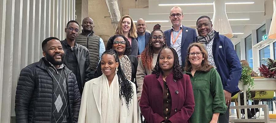 12 people smiling and standing on the steps at internal steps at IRR as part of a delegation from Botswana.