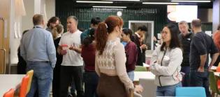 many people standing in a cafe in small groups conversing