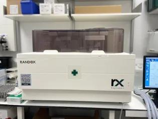 Randox Daytona+ analyser on the lab bench, showing sample tray, touchscreen interface, and reagent compartments.