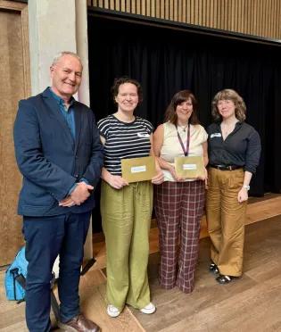 Stuart Forbes, Lauren Melrose, Shonna Johnston, and Florence Gohard standing in a line in front of a black curtain
