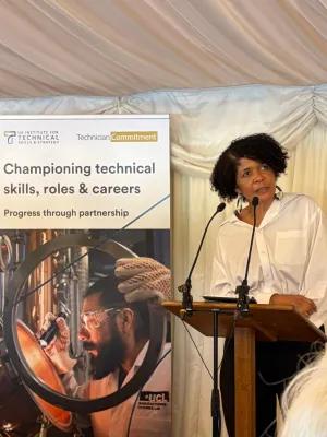 Dame Chi Onwurah giving a speech behind a lectern and in front of the event's banner