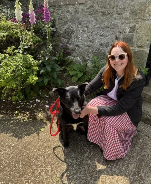 Abbie wearing sunglasses next to a big black dog