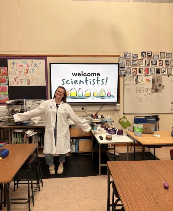Lucy stood in a classroom wearing a labcoat